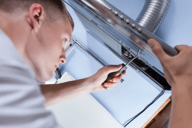 A man working on an exhaust fan.